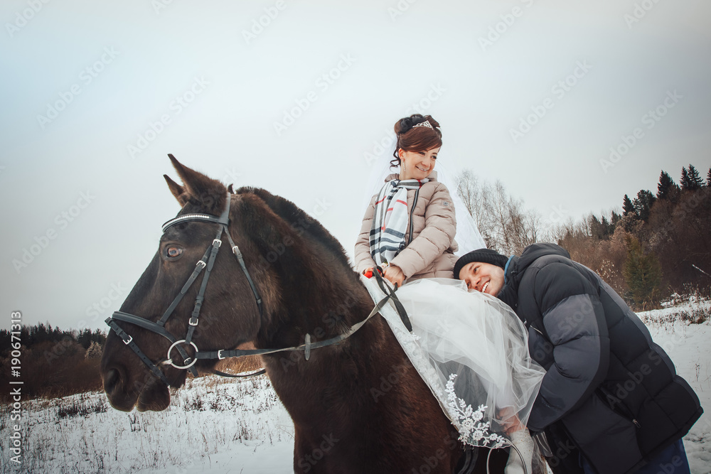 Bride and groom walking with horse in a winter afternoon Bride and groom walking with horse in a winter afternoon