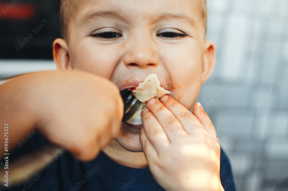 A hungry child is eating dumplings in the kitchen