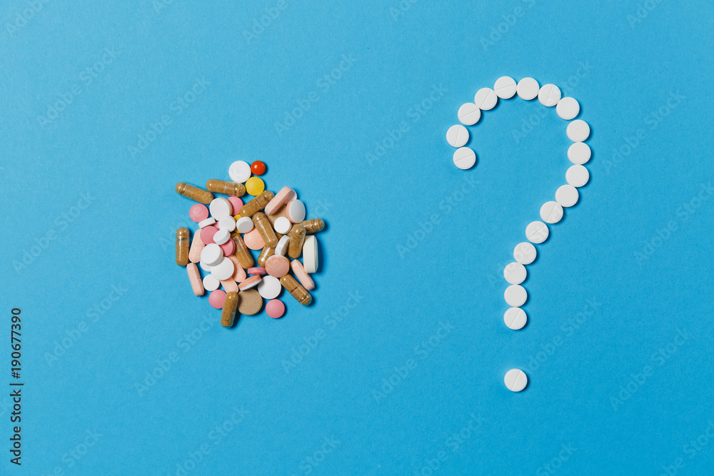 Medication white round tablets arranged in question mark shape isolated on blue color background. Bunch of multicolored pills, colorful sign. Concept of health, treatment, choice, healthy lifestyle. Medication white round tablets arranged in question mark shape isolated on blue color background. Bunch of multicolored pills, colorful sign. Concept of health, treatment, choice, healthy lifestyle.