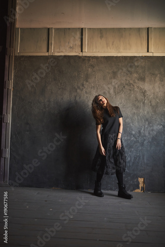Portrait beautiful woman with elegant black dress. Pretty young woman standing against grunge background. Lady before evening party or meeting looking in window.