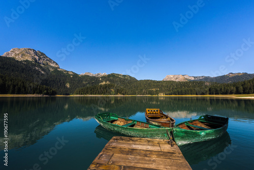Durmitor National Park - Mountain lake Black Lake "Crno jezero" with wooden boats and reflections of mountain range in clear water, Montenegro, Europe