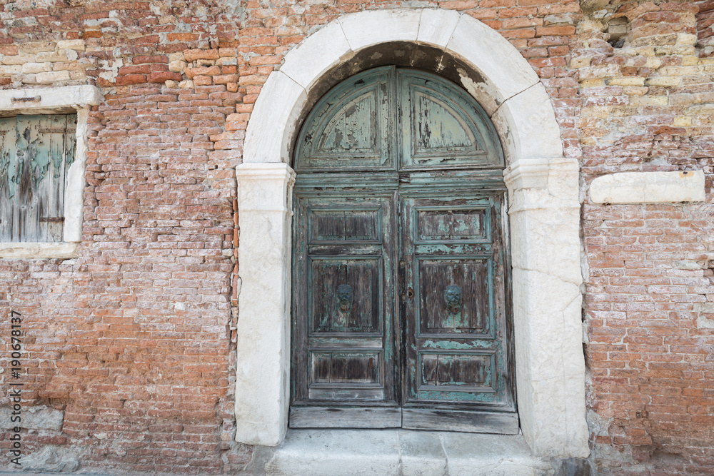 antique large decorative wooden door in a brick building