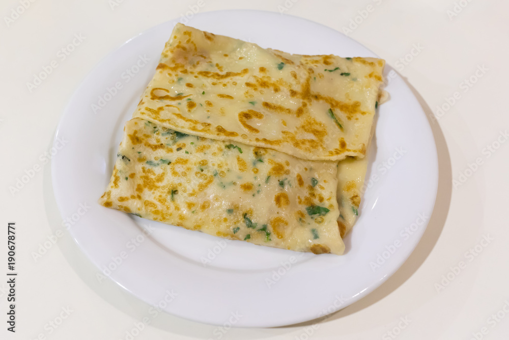 Russian pancake with filling on a white plate