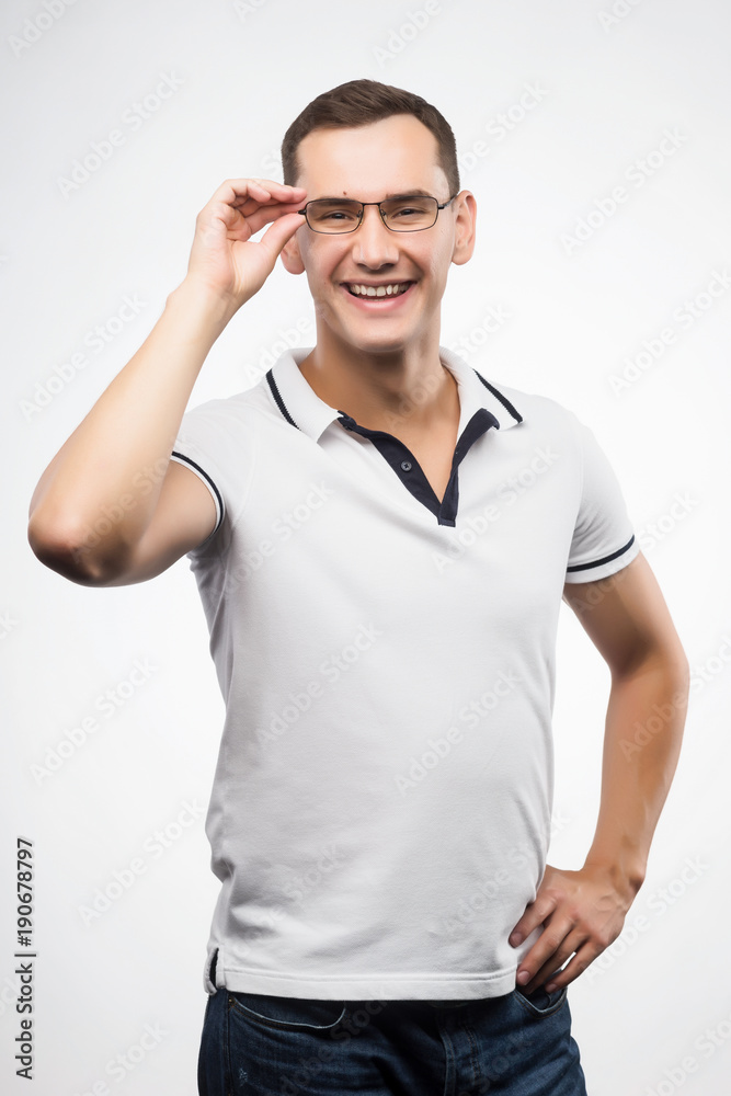 A young positive man in eyeglasses straightens his glasses with his hand. Emotional, courageous face. Isolated on white background. Copy space. A young positive man in eyeglasses straightens his glasses with his hand. Emotional, courageous face. Isolated on white background. Copy space.