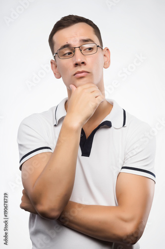 A young positive man in eyeglasses thinks. Emotional, courageous face. Isolated on white background. Copy space. © Алексей Торбеев