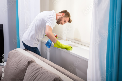 Janitor Cleaning Windowsill With Sponge