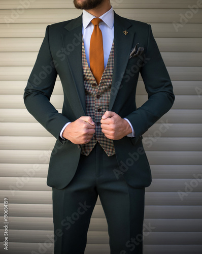 Attractive man in tailored suit posing in front of background