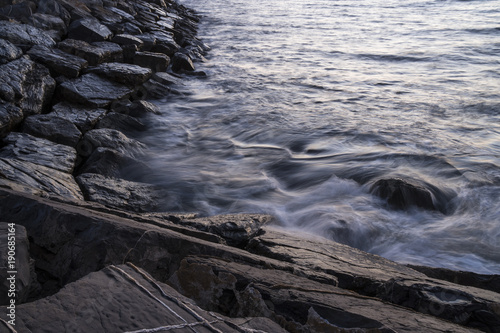 Sea coast with rocks at dawn, long exposure with water and moving waves.