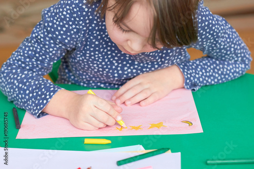 The child draws at the table in the kindergarten.