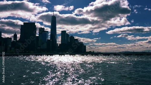 Dramatic scenic timelapse of winter clouds moving across a silhouette of the New York City skyline with sun sparkling on the Hudson River