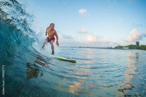 Surfer rides the wave during sunrise surf session. Maldives