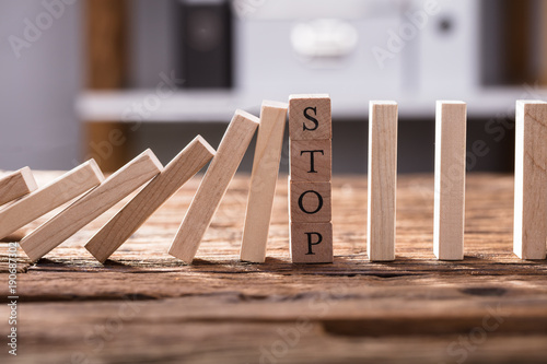 Foto Falling Dominos Stopped By Wooden Blocks Showing Stop Text