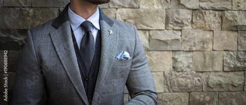 Suited man posing in front of wall background