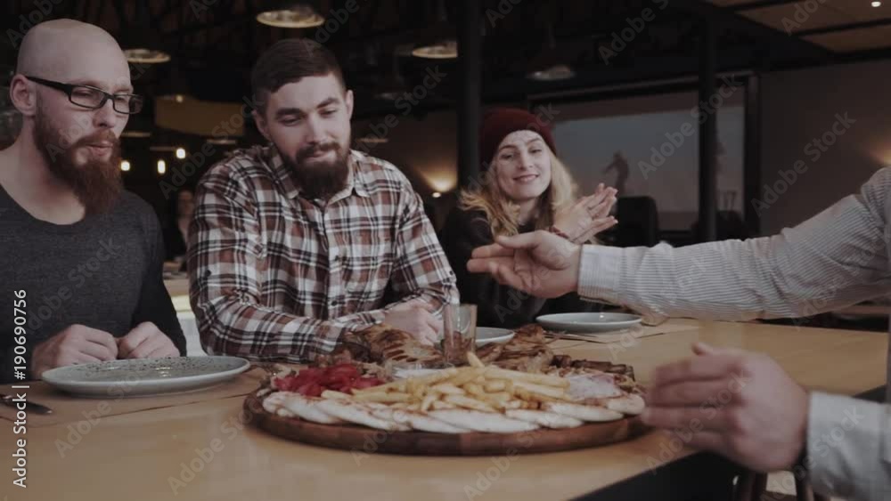 Group of young adults are getting their order of a meat plate at the cafe Group of young adults are getting their order of a meat plate at the cafe