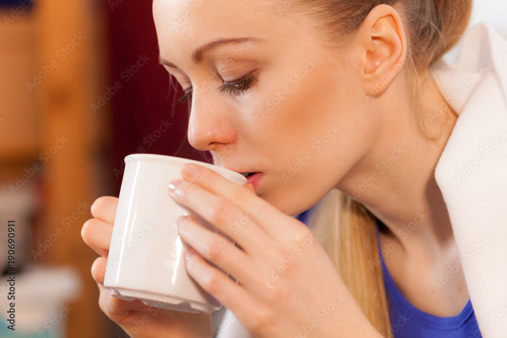 Woman lying on sofa under blanket drinking tea Woman lying on sofa under blanket drinking tea