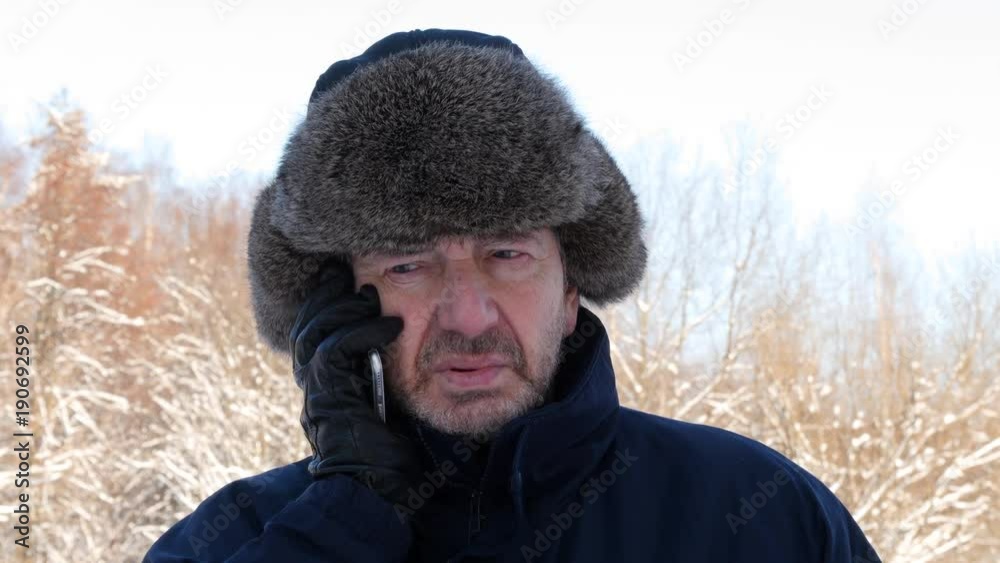 Elderly Bearded Man Talking On Mobile Phone In The Winter Forest Elderly Bearded Man Talking On Mobile Phone In The Winter Forest