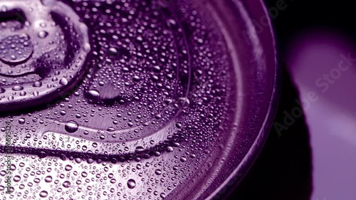 Red beverage can with soda rotates on a dark background. Water drop and bubbles. The play of light and shadow photo