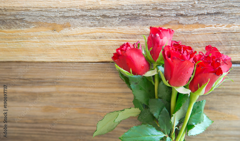 Bunch of red roses on wooden background.