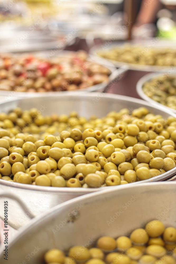 Close up of an aluminium bowl in an asian food market filled with seedless green olives