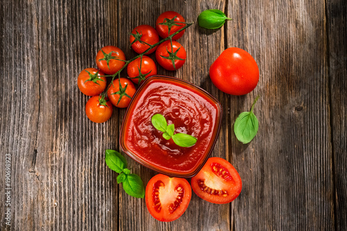 Tomato sauce and fresh tomatos on rustic background