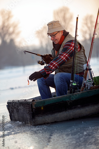 Man on winter fishing on the frozen lake