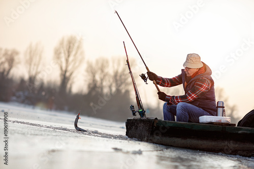 ice fishing on frozen lake- fisherman catch fish