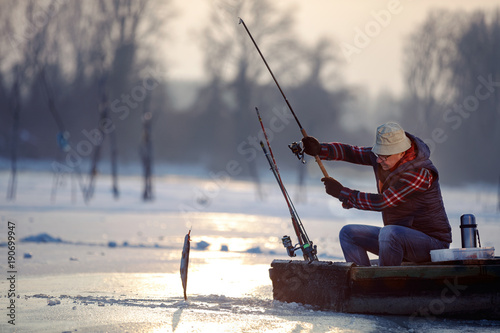 elderly fisherman fishing on frozen lake