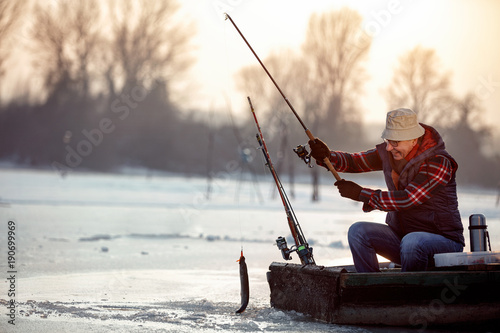 ice fishing on frozen lake- smiling fisherman catch fish