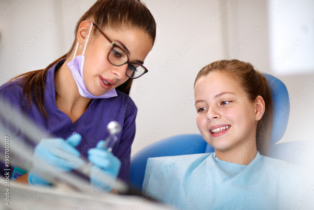 Dentist showing instrument for repairing teeth to girl in dental chair Dentist showing instrument for repairing teeth to girl in dental chair