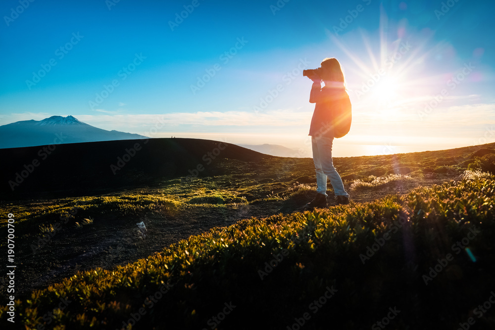 Hiker takes pictures from top of the mountain during sunset using the best of the golden hour - obrazy, fototapety, plakaty 