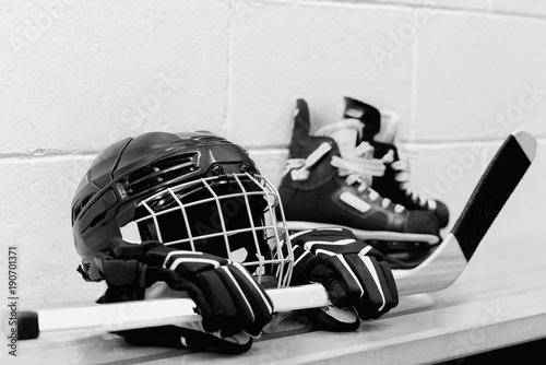 White and black photo of girl's hockey gear: helmet, gloves, sticks, skates with laces