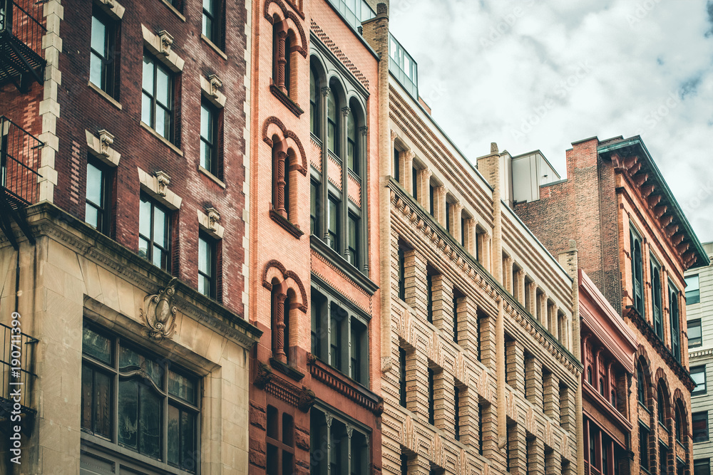 Row of vintage New York City apartment buildings in a variety of brick and brownstone facades