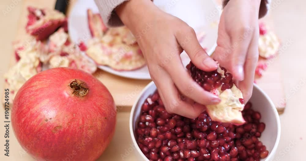 Putting Fresh red pomegranate into bowl