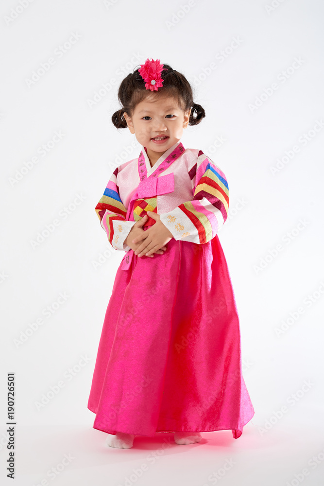 Smile Korean little girl wearing a Traditional Hanbok dress in white background. The characters on the dress means happiness and healthy. Smile Korean little girl wearing a Traditional Hanbok dress in white background. The characters on the dress means happiness and healthy.