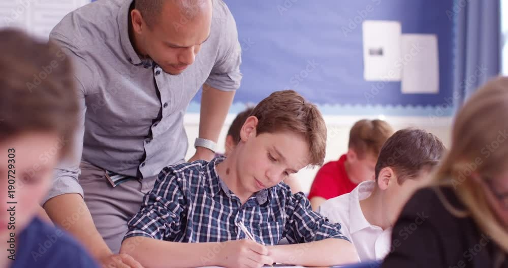 4k, A teacher helping his students with their work in the classroom. 4k, A teacher helping his students with their work in the classroom.