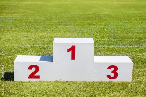 White wooden winner podium placed on green grass sport field on a sunny day photo