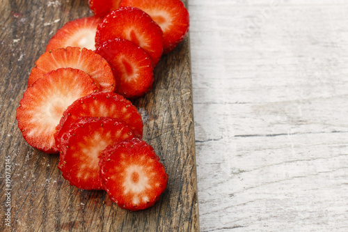 Sliced strawberries on wooden cutting board