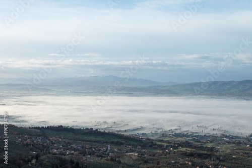 Beautiful view of Umbria valley in a winter morning, with fog covering trees and houses