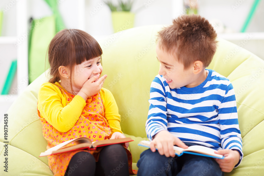 Little girl and boy reading and laughing Little girl and boy reading and laughing