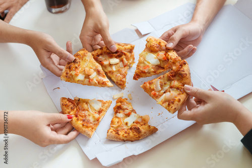 People eat fast food. Friends hands taking slices of pizza