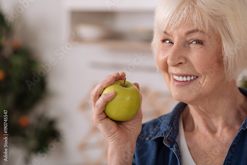 Joyful senior woman holding an apple photo