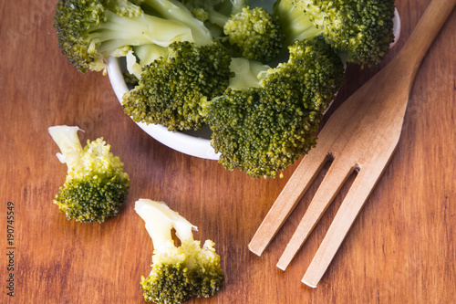 bowl of cooked green broccoli on wooden background and copyspace