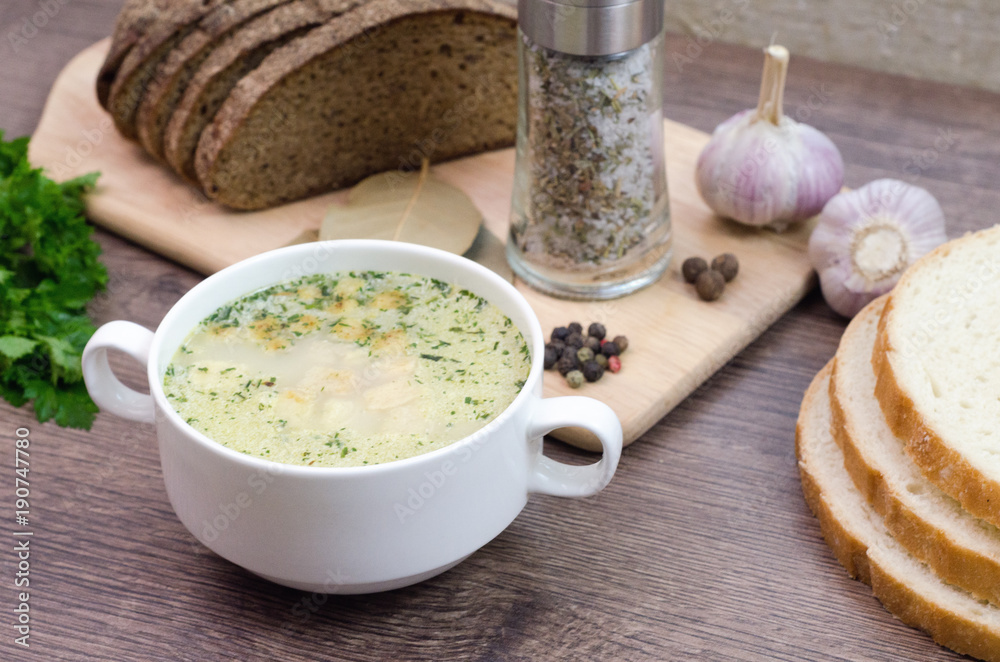 Mushroom soup with croutons in a white dish is on a wooden table. Mushroom soup with croutons in a white dish is on a wooden table.