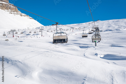 Sunny day in the Alps - ski tracks, ski lifts and snowy mountains