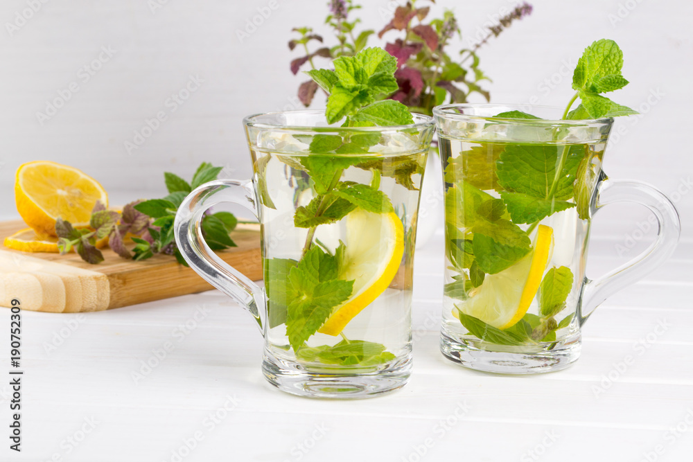 Two glass cups fresh mint tea with lemon and a bunch of mint in vase Two glass cups fresh mint tea with lemon and a bunch of mint in vase