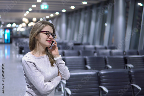 Young, beautiful girl talking on the phone in an empty airport terminal