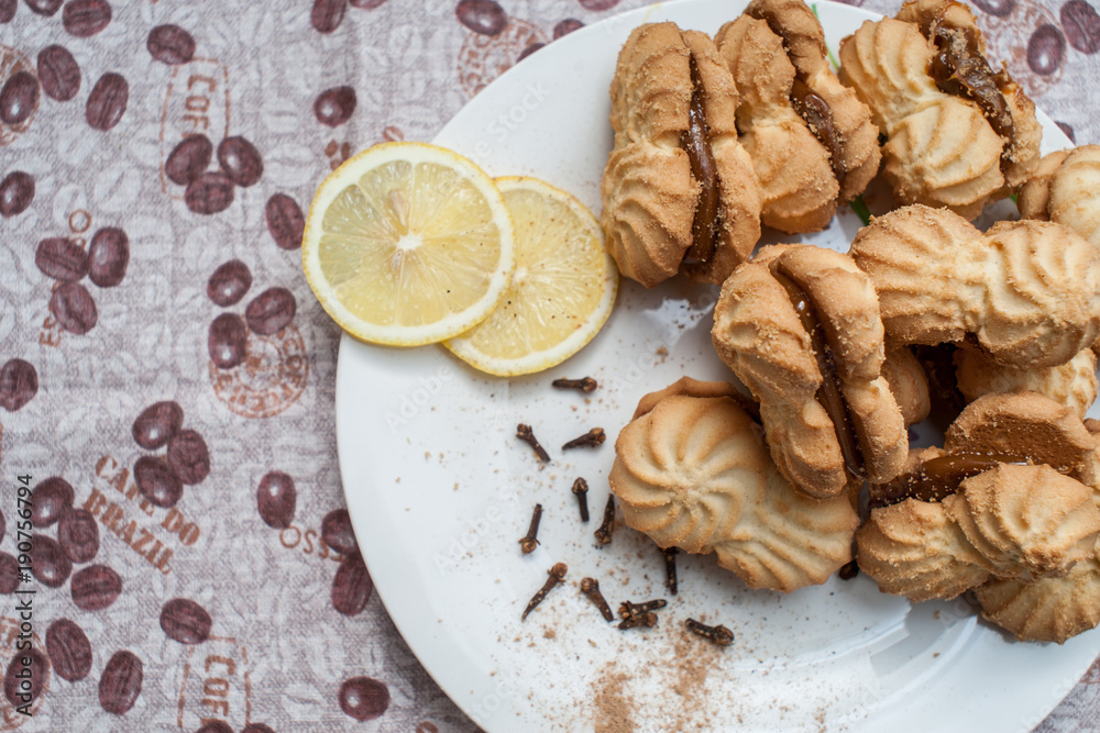 cookies on a plate with condensed milk with lemons under a coffee cookies on a plate with condensed milk with lemons under a coffee