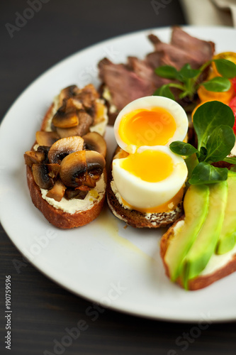 Bruschetta, assorted, different fillings, on plates with a soft-boiled egg in the middle