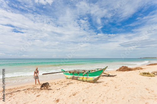 Balapitiya, Sri Lanka - A woman and a dog going out for a walk at the beach of Balapitiya