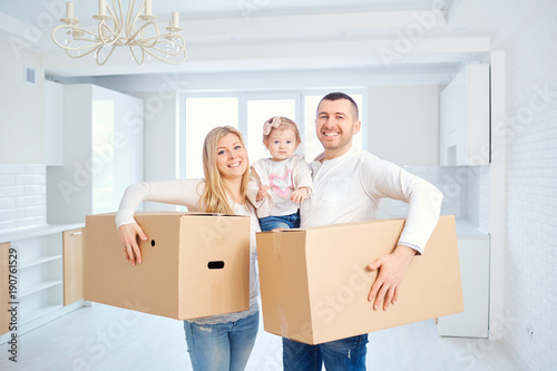 A happy family moves to a new apartment. Mother, father and child with boxes in the room of the new house.
